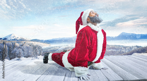 Santa Claus in traditional red white costume in front of white snow winter landscape panorama. Christmas, x-mas, gifts concept.