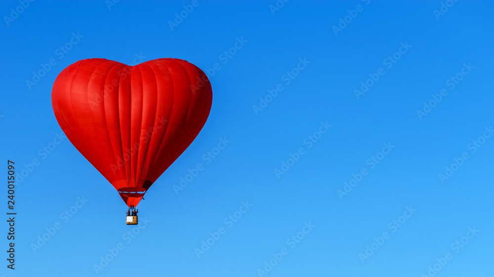 red balloon in the shape of a heart against the blue sky
