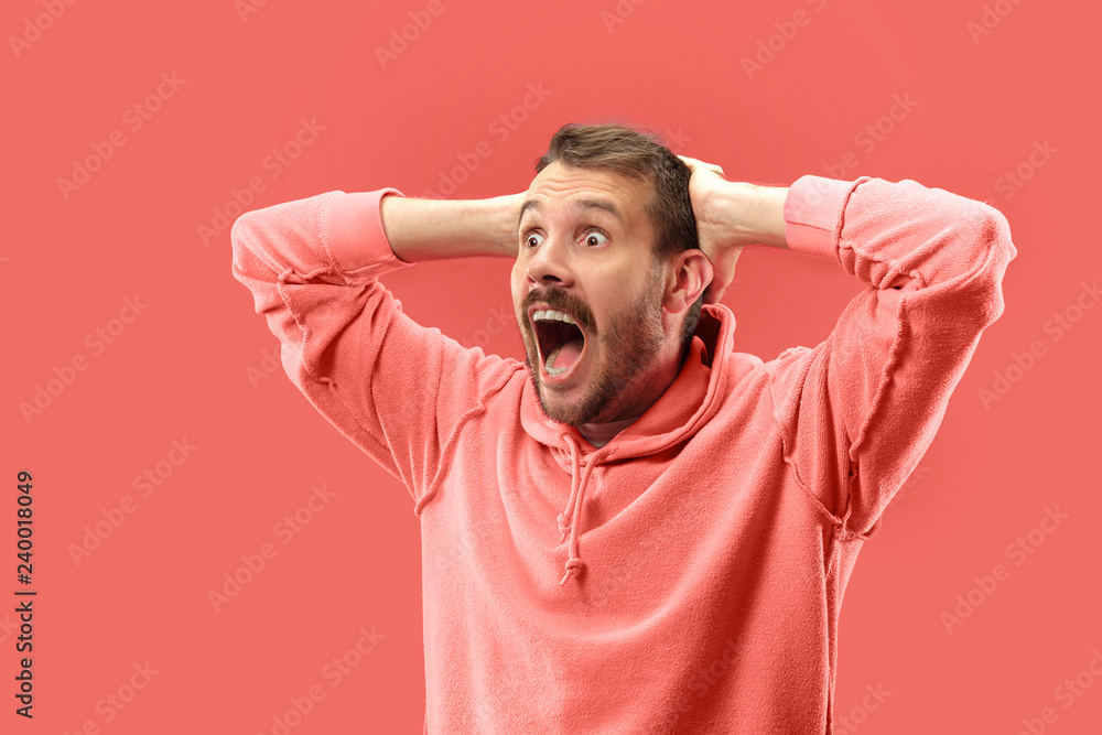 Wow. Attractive male half-length portrait on coral studio backgroud. Young emotional surprised bearded man standing with open mouth. Human emotions, facial expression concept. Trendy colors Wow. Attractive male half-length portrait on coral studio backgroud. Young emotional surprised bearded man standing with open mouth. Human emotions, facial expression concept. Trendy colors