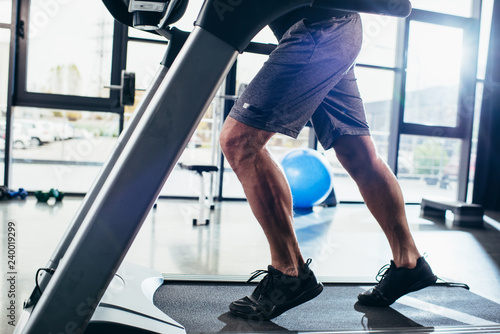 cropped image of sportsman running on treadmill in gym