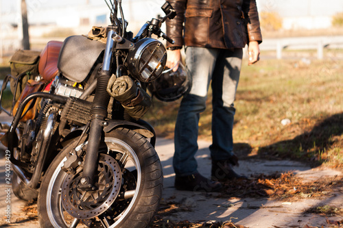 Man and old custom cafe-racer Motorcycle on forest  at sunset photo