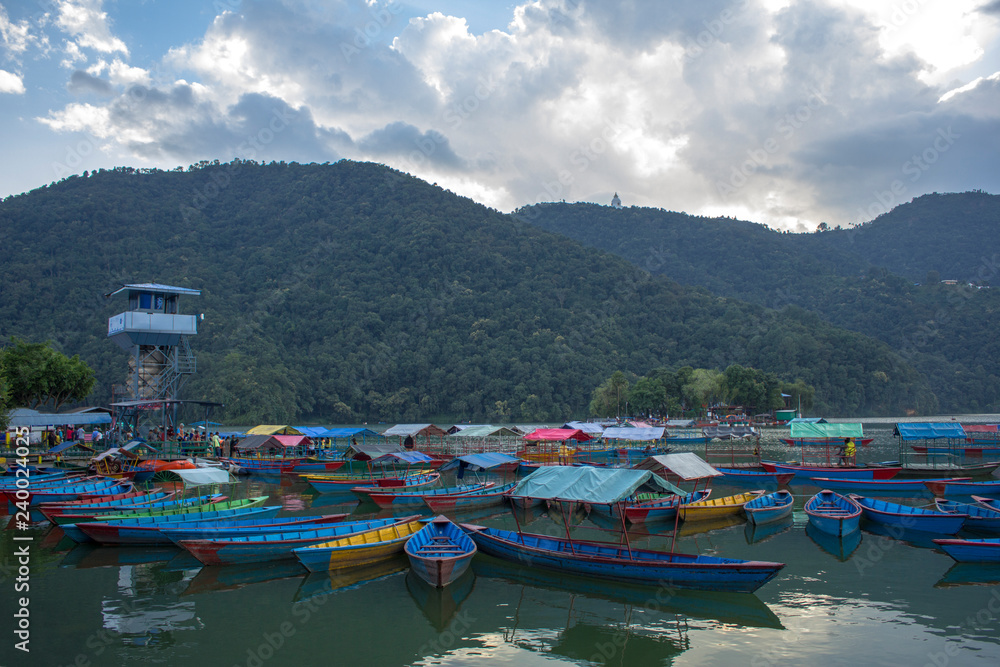 old wooden colored boats on the lake near the pier in the evening against the backdrop of the mountains