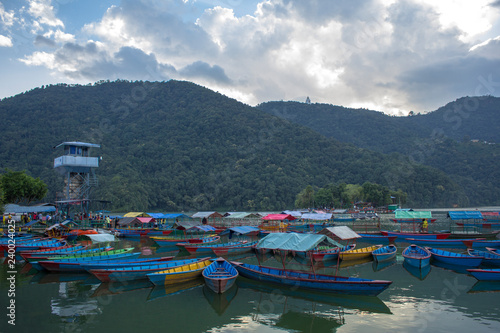 old wooden colored boats on the lake near the pier in the evening against the backdrop of the mountains
