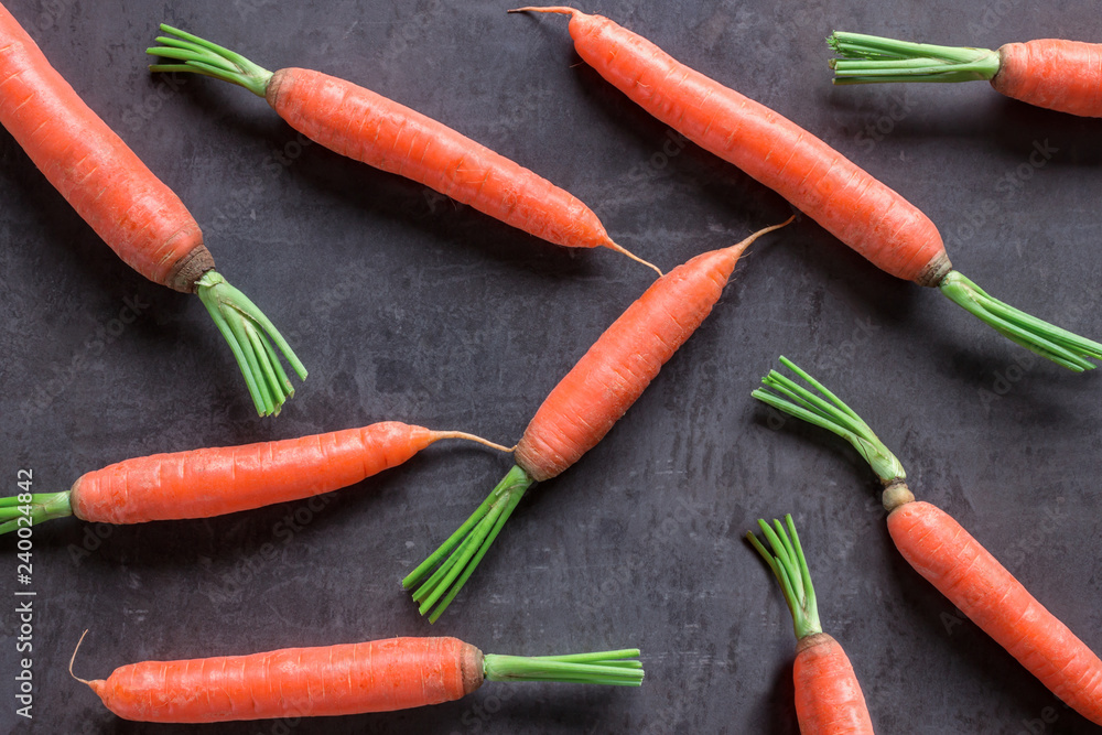 Bright ripe carrots with leaves on the table. Concept-healthy food, vegetarianism, raw food, a source of carotene and vitamins A,B . Bright ripe carrots with leaves on the table. Concept-healthy food, vegetarianism, raw food, a source of carotene and vitamins A,B .