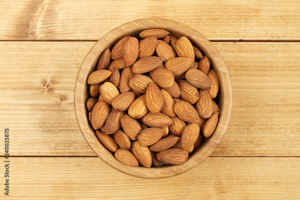 Shelled almonds in bamboo bowl on wooden background Shelled almonds in bamboo bowl on wooden background