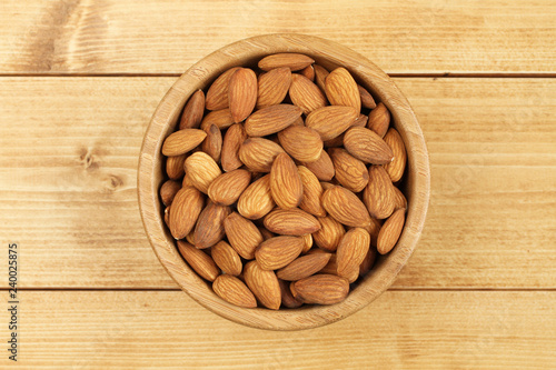 Shelled almonds in bamboo bowl on wooden background