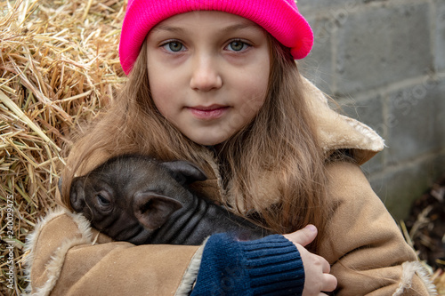 Adorable little childs in colorful clothers playing with just born piglets in winter fermers yard. Creative leisure with kids on swine farm photo