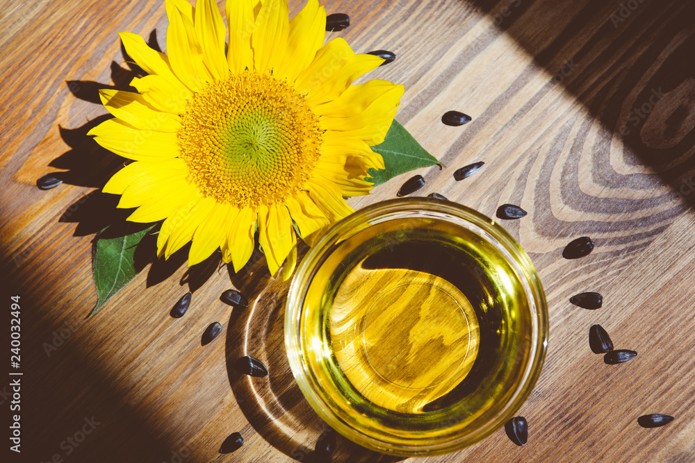 Oil and yellow sunflower in bowl and seeds around, food concept Oil and yellow sunflower in bowl and seeds around, food concept