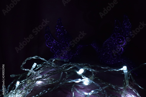 Two beautiful violet birds Christmas tree toys in the dark sparkle, shine, look at each other in the background white lights