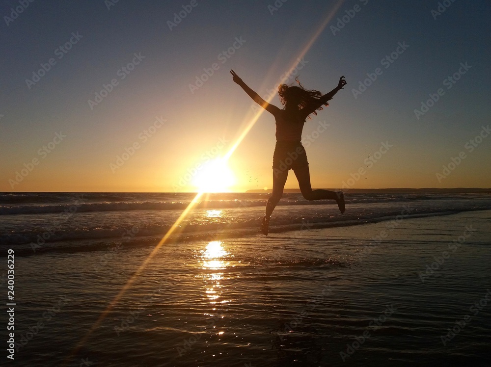 Mujer saltando en la playa