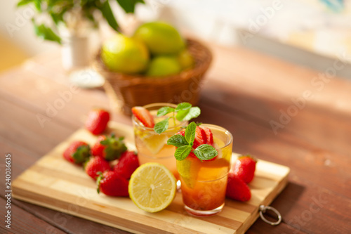 Refreshing summer drink with lemon, strawberry and mint on wooden table