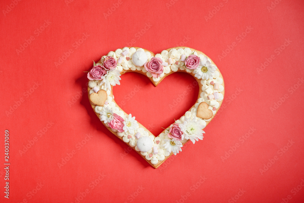 Valentine's Day heart-shaped cake with flowers as decoration. The concept of a gift to a loved one on a holiday.
