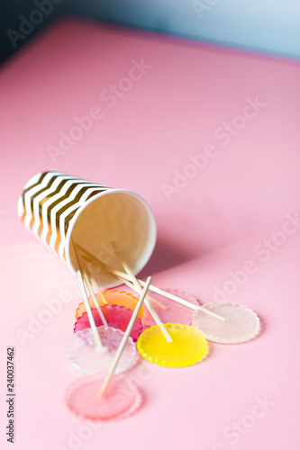 multi-colored lollipops on a pink background in a paper golden glass