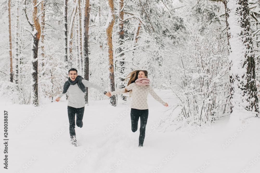  couple in love walking in the snowy forest, hugging, kissing and enjoying