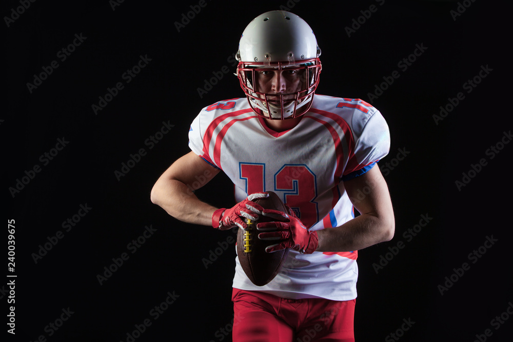 American football player wearing helmet ready to throw ball on black background