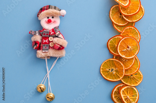Dried slices oranges citrus fruit and funny snowman on light blue background. Homemade natural aroma decor. Concept of holiday. Marry Christmas. Close up, flat lay, top view