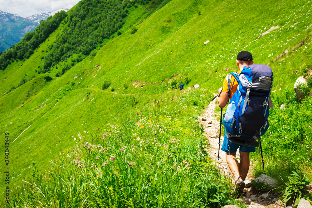 Tourist with backpack on hiking trail in mountains