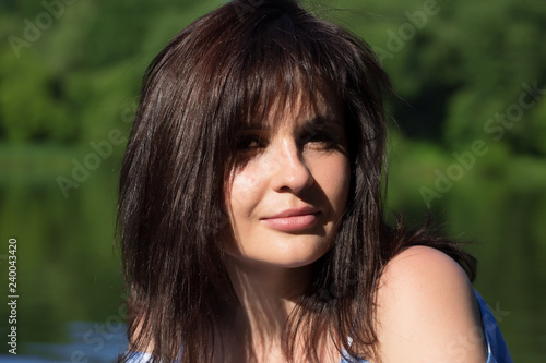Close up portrait of a woman with dark dissolved hair. She looks at the viewer and smiles.