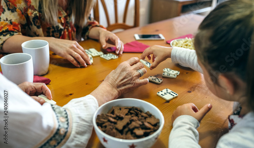 Unrecognizable grandmother, daughter and granddaughter playing domino in the living room