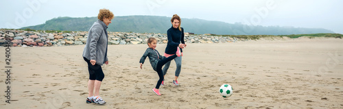 Three generations female playing soccer on the beach in autumn © David Pereiras