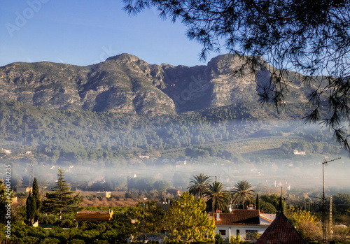 View of montains and spanish village in the valley in  morning mist