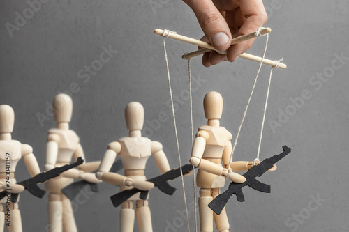 Concept of war. People with weapons, armed protest, terrorists. The puppeteer controls the doll with gun, the provoker leads crowd of people with weapons