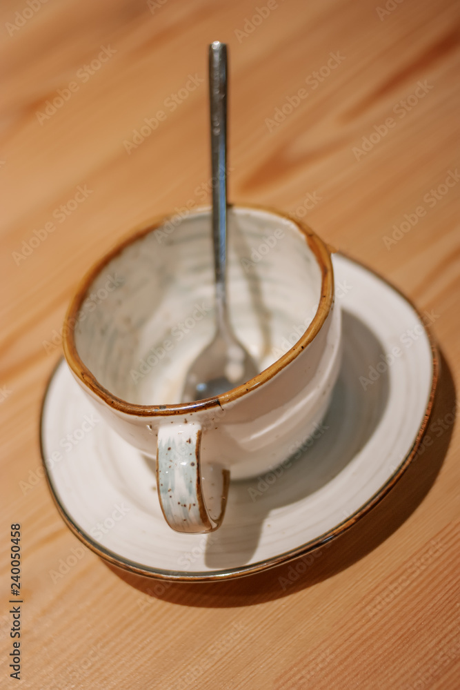Empty ceramic mug on wooden table with spoon inside Empty ceramic mug on wooden table with spoon inside