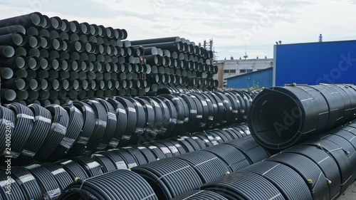 Warehouse of finished plastic pipes industrial outdoors storage site. Manufacture of plastic water pipes factory. Process of making plastic tubes on the machine tool with the use of water and air