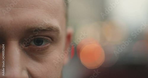 Close up of the hald face and an eye of the Caucasian man looking straight with serious look. City lights on the background. Outdoor. photo