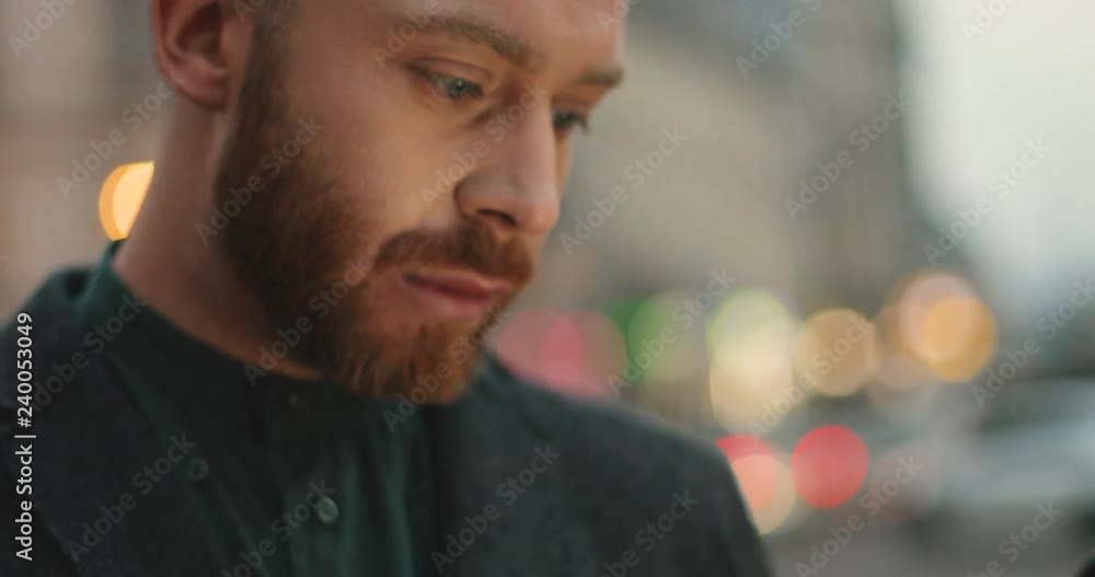Close up of the Caucasian young man holding his smartphone, typing and texting on it. Outdoors. Close up of the Caucasian young man holding his smartphone, typing and texting on it. Outdoors.
