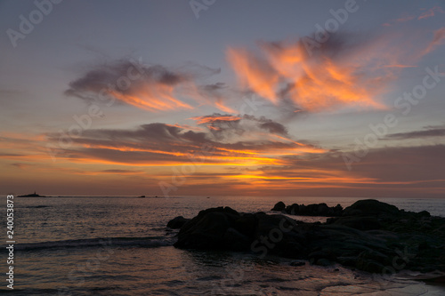 Colorful ocean beach sunset with a few clouds