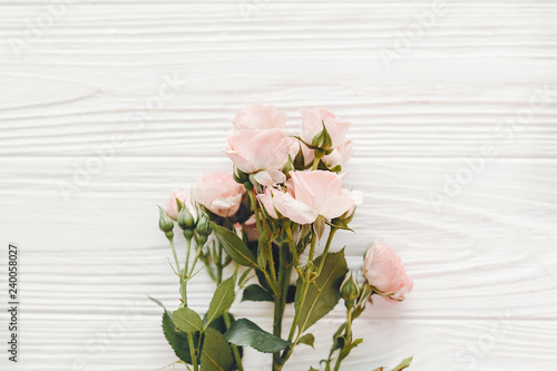 Pink small roses on wooden background  flat lay with space for text. Floral greeting card mockup. Wedding invitation happy mother day or Valentine day concept. Hello spring.