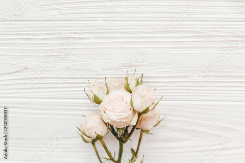 Pink small roses on wooden background  flat lay with space for text. Floral greeting card mockup. Wedding invitation happy mother day or Valentine day concept. Hello spring.
