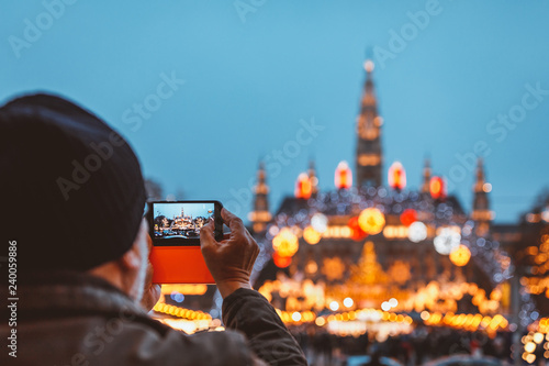 Man taking photo of Christmas market at Vienna City Hall in blue hour light photo