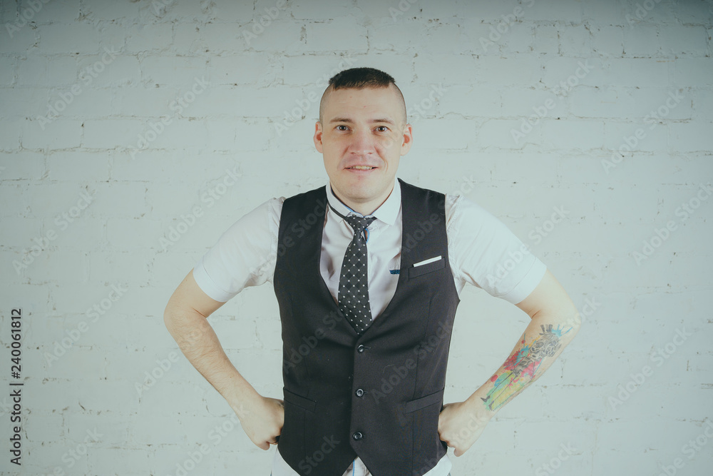 Emotional office worker with a tattoo, posing against a white brick wall. The man is dressed in jeans and a white shirt with a tie. Emotional office worker with a tattoo, posing against a white brick wall. The man is dressed in jeans and a white shirt with a tie.