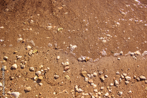 bright vivid yellow sea sand and stones shoreline background texture surface