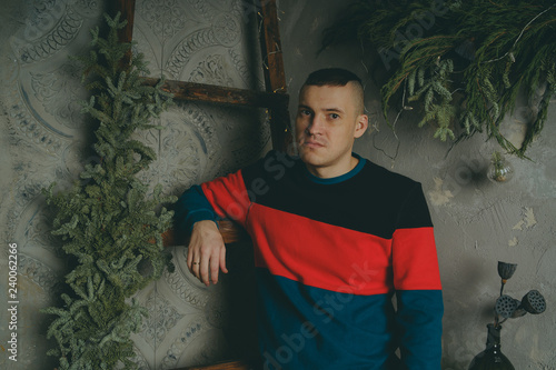 A young man posing on the background of the stairs, a guy with a short haircut posing on the background of the stairs