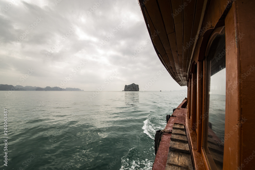 A tourists boat is sailing on the water of Ha long Bay in Vietnam. Ha Long Bay, in northeast Vietnam, is known for its emerald waters and thousands of towering limestone islands topped by rainforests.