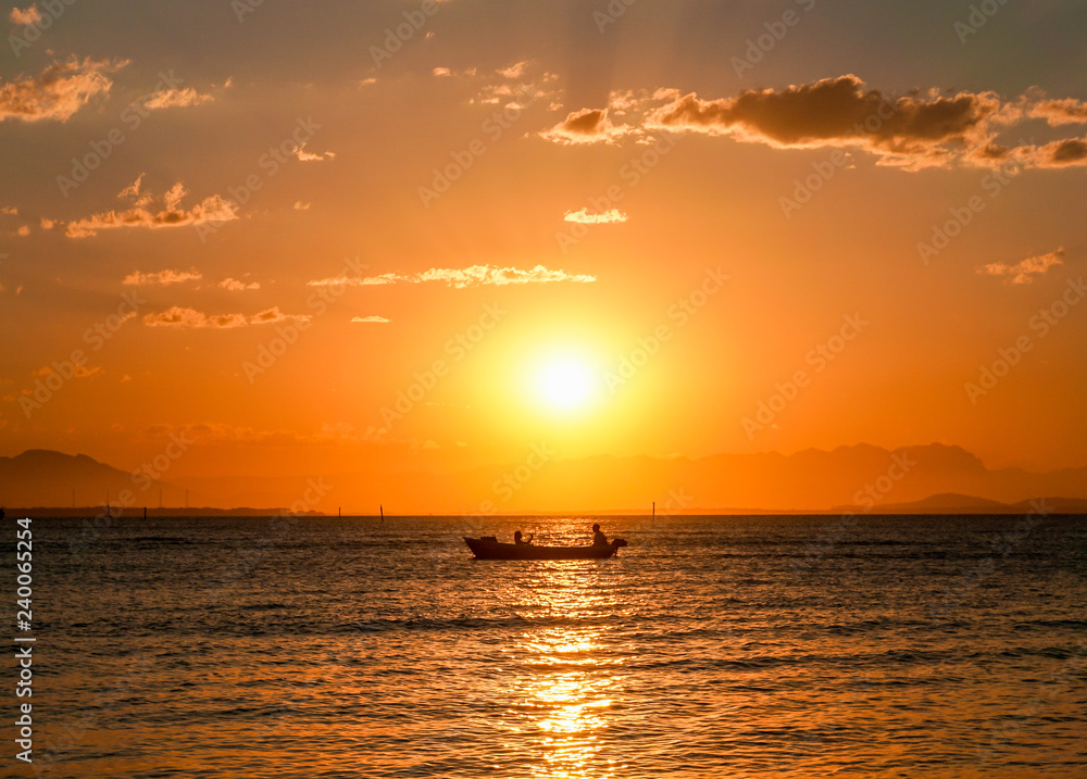 Silhouette of a couple in a small boat enjoying the sunset in Ilha do Mel, Paraná, Brazil