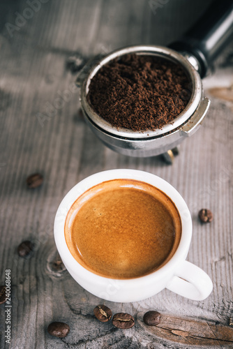 Fresh tasty espresso cup of hot coffee with coffee beans and Coffee maker on wood table background