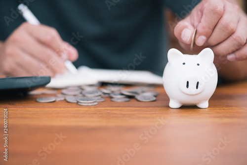 Saving money concept Man hand putting coin on piggy bank and write Finance.save money concept.