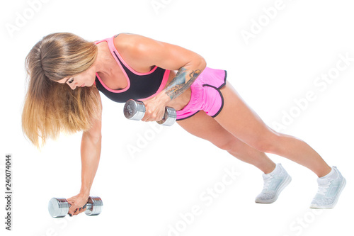 Attractive, sexy, muscular girl in pink shorts and a black top doing plank- exercise with steel-color dumbbells. Fitness, healthy lifestyle concept. Isolated on the white background.