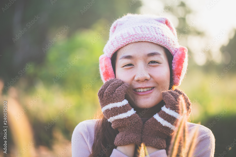 Beautiful young woman standing outdoor with warm clothes and gloves and earmuff standing on a warm morning background in the winter. Beautiful young woman standing outdoor with warm clothes and gloves and earmuff standing on a warm morning background in the winter.