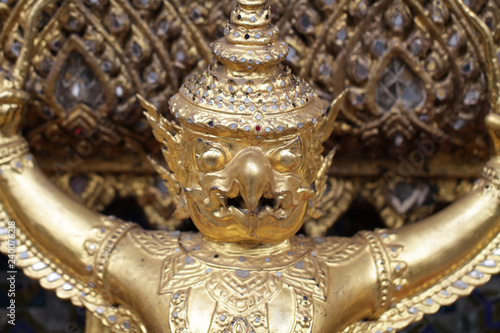 close up golden Garuda statue stand around , the bronze symbol of Thai government, giant ancient gold eagle with crown sculpture antique signature on temple royal palace wall