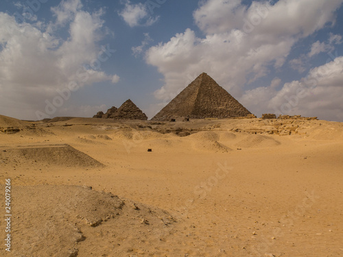 The great Pyramids in a sandy desert with blue sky and clouds