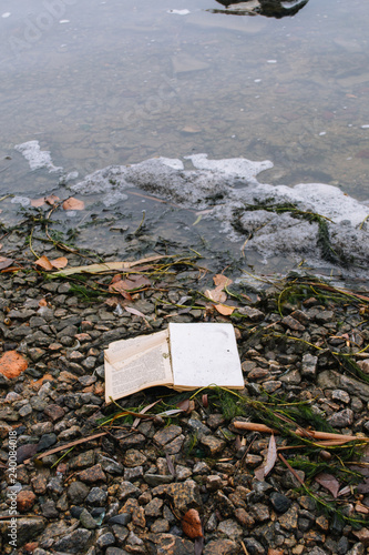 Forgot book on the river bank. Broken book on the river side. Book on the stones rubbly coast.  photo