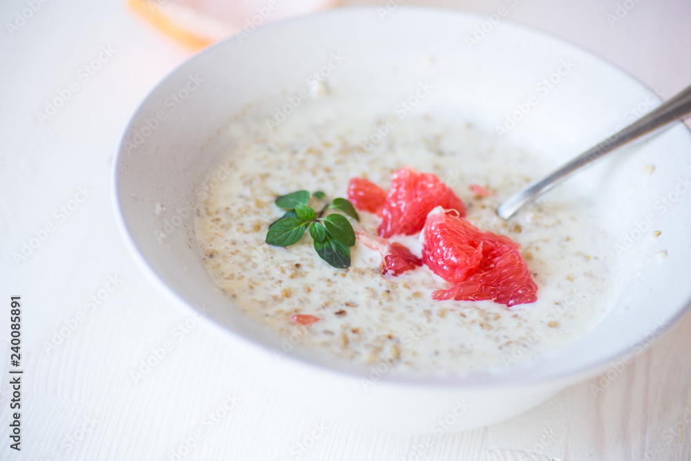sweet oatmeal with slices of red grapefruit in a ceramic bowl