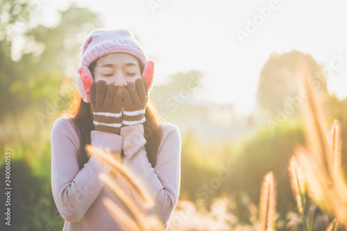 Young woman standing outdoors, wearing knitted sweaters and gloves, and earmuff in the morning, Copy space.