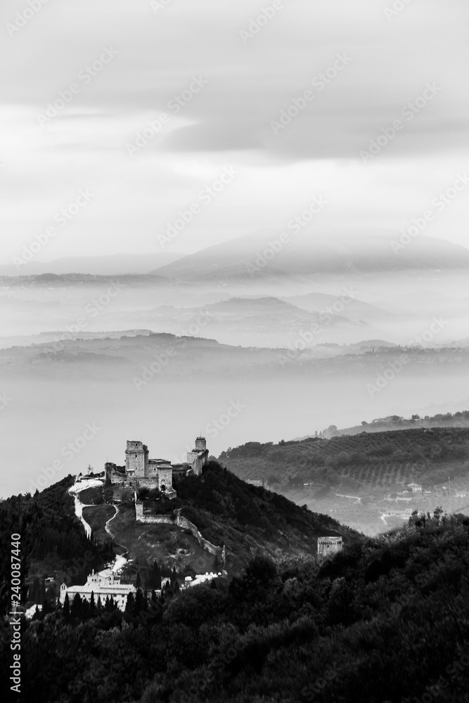 Beautiful view of Rocca Maggior castle (Assisi, Umbrfia, Italy) over a sea of fog with distant hills in the background Beautiful view of Rocca Maggior castle (Assisi, Umbrfia, Italy) over a sea of fog with distant hills in the background