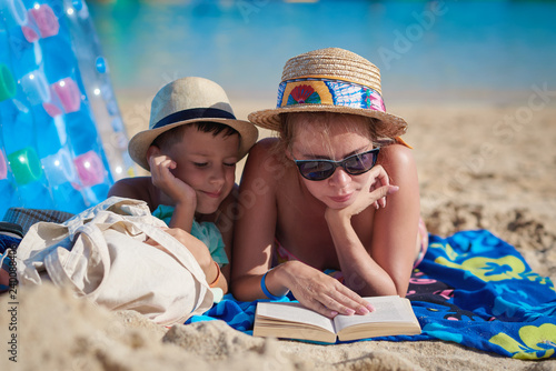 Bild auf Leinwand Mom and son reading an interesting book at the beach